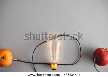 Conceptual photography for communication and brainstorming. Two apples with glowing light bulb in between connected by a wire
