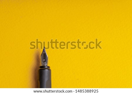 Fragment of an ink pen on a yellow background. Copyspace