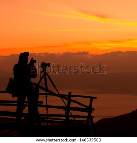 Silhouette of photographer on the top of mountain.