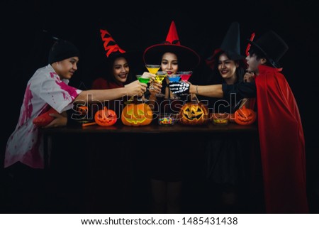 group of asian friends in spooky costume having fun in halloween celebration party at nightclub and clinking cocktail together
