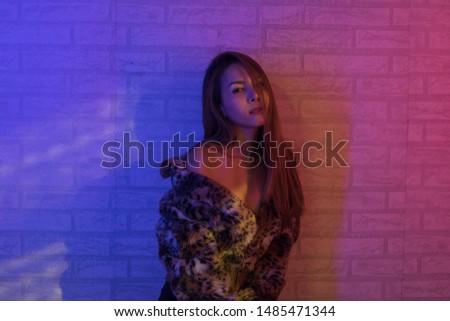 Beautyful woman photo fashion portrait with blue color and red color light with brick wall background, pretty modern style fashion.