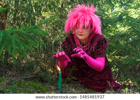 A young sorceress in purple clothes conjures a candle dug into the ground.
