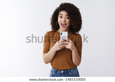 Say cheese. Cheerful attractive amused happy curly-haired girlfriend holding smartphone taking picte friend asking smile make selfie mirror excited standing white background upbeat