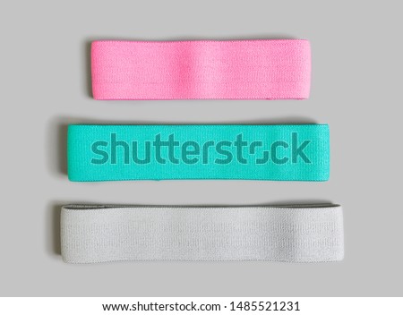 Resistance bands for exercise and physical therapy in three colors and sizes isolated on gray background