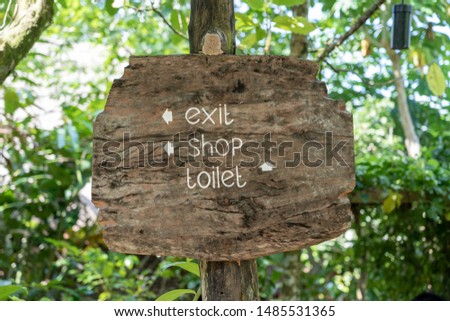 Text exit, shop and toilet on a wooden board in a rainforest jungle of tropical Bali island, Indonesia. Exit, shop and toilet wooden sign inscription in the asian tropics. Close up