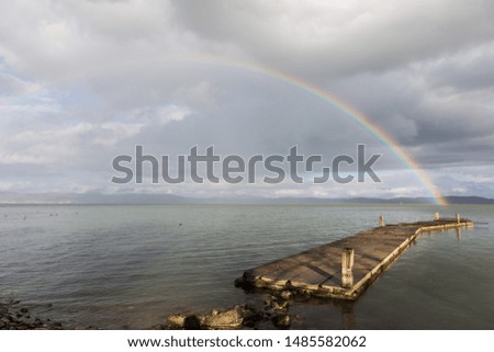 Beautiful view of a rainbow over a pier on a Trasimeno lake (Umbria, Italy)