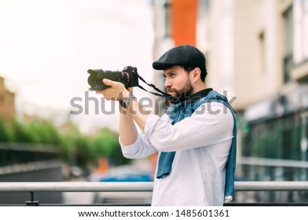 Young man with camera photographing at street