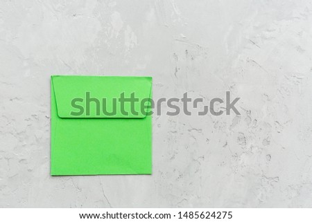 Minimal composition with green envelope on a gray concrete background. Mockup, copy space, overhead. Flat lay. Top view.