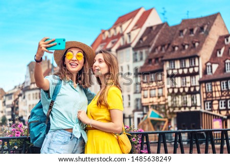 Two multicultural girl friends take a selfie on smartphone while traveling in European old cities. Vacation and relationship concept