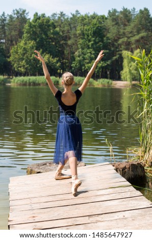 beautiful ballerina dancing on a wooden bridge in a park by the lake