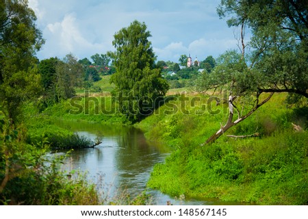 Typical Russian village landscape with the river and the church in the distance