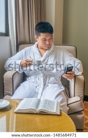 Vertical photo of businessman wearing bathrobe and enjoy morning coffee