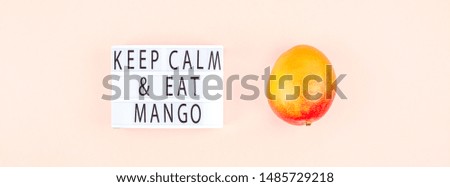 Mango fruit in creative conceptual top view flat lay composition with lightbox with Keep calm and eat mango slogan isolated on pink background in minimal style with copy space. Pop art concept poster