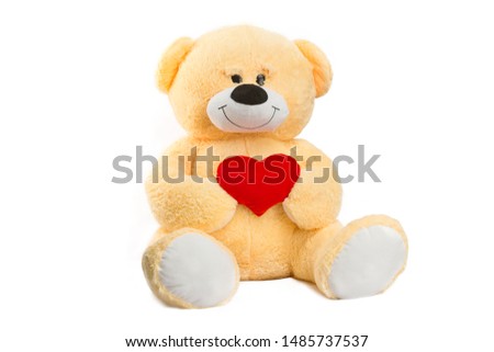 Image of golden toy teddy bear holding red heart and sitting at isolated white background.