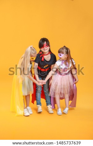 Cute little children dressed as superheroes on color background