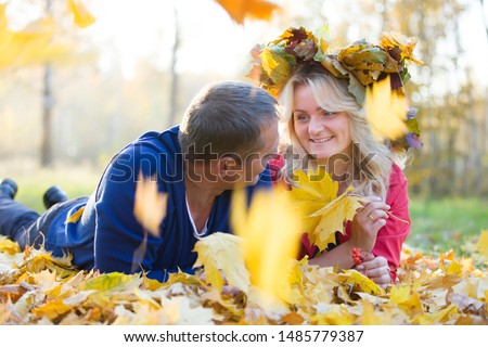 Loving couple in the autumn park. Spouses of middle age for a walk.Men and woman lie in the yellow autumn leaves in the park