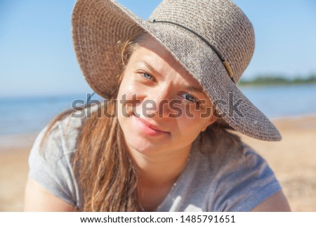 Portrait of brunette beautiful woman in straw hat without makeup on sunny summer day on beach
