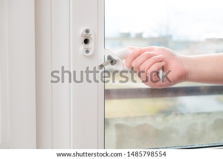 A man holds in his hand a broken doorknob. The door is closed due to negligence and the use of high power or due to defective parts