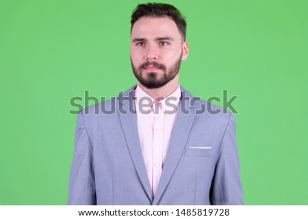 Face of young handsome bearded businessman thinking