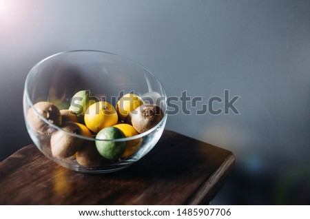 Citrus fruits kiwi lemon lime  in a glass vase close-up on gray background