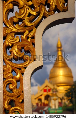 The golden pattern of the outdoor wood engraving, the background is the blurred Shwedagon Pagoda in Yangon, Myanmar.