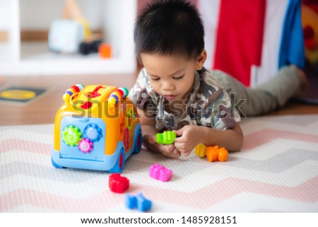 Asian baby playing the shape sorting truck in the living room.