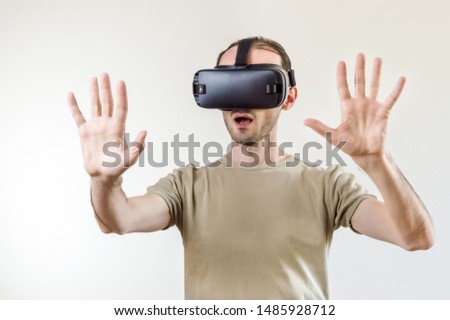 Caucasian man in t-shirt wearing virtual reality goggles on white background. Future technology concept.