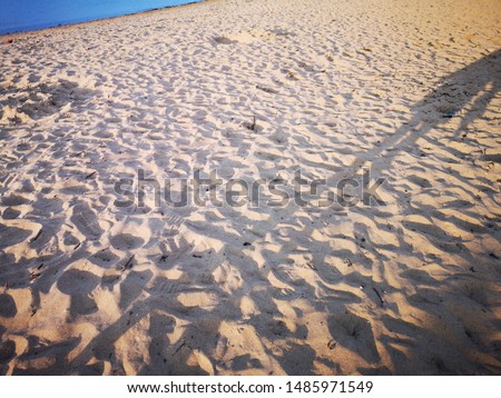 A sandy beach with pebbles washed up and footprints 