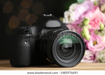 Modern camera and bouquet on wooden table. International Photographer's day