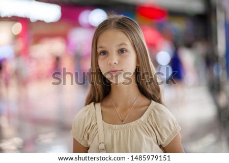 A beautiful young girl is standing in a shopping center. She thought about something. Children's Day. Child protection.