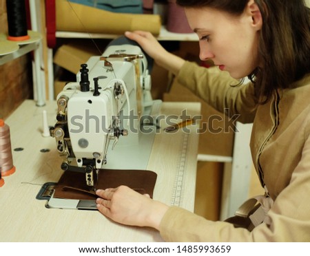 Closeup on young woman sewing leather handbag