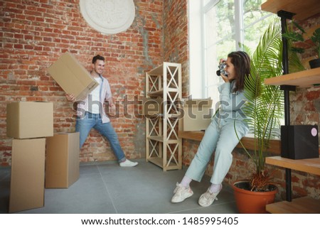 Build the future together. Young couple moved to a new house or apartment. Look happy and confident. Family, moving, relations, first home concept. Making photo, laughting while unpacking their things