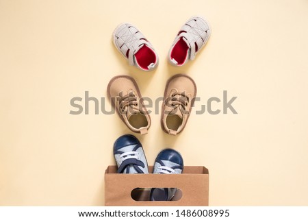 Shopping bag and baby boots on an orange background. Royalty-Free Stock Photo #1486008995