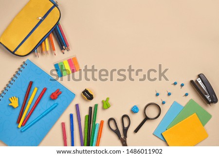 Flat lay photo of workspace desk with school accessories or office supplies on pink background.
