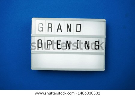 Top view Grand opening word in light box flat lay with space copy on blue background;