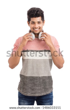 Handsome young Indian man standing with headphones
