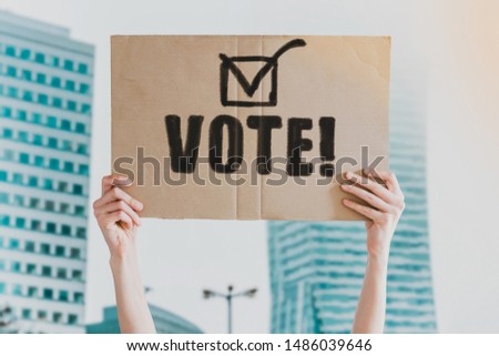 The word " Vote " and check mark icon drawn on a carton banner in men's hand. Human holds a cardboard with an inscription: Vote