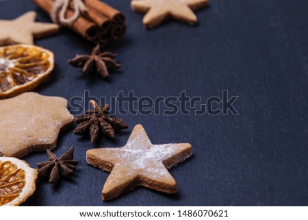 Gingerbread, cinnamon and dried oranges on a dark background. Copy spase.