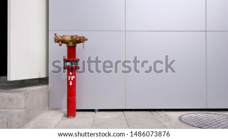 The red fire department connection on concrete floor with gray tiles wall background outside of the building