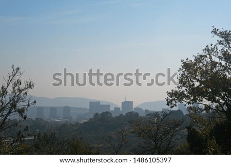 VIEW OF SMOG COVERED URBAN AREA FROM A VEGETATION COVERED HILL