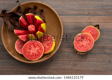 Guava fruit, chopped in the shape of a star, in an earthenware bowl. Aged wood background pieces. Top view. From above. Space for text. Horizontal. Royalty-Free Stock Photo #1486125179