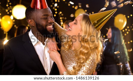 Glad mixed-race couple in party hats celebrating birthday, holiday entertainment