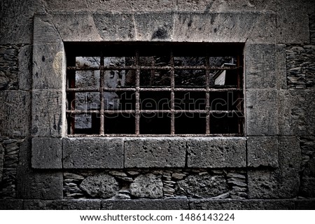 Prison cell window with bars, old stone citadel architecture detail.   Royalty-Free Stock Photo #1486143224