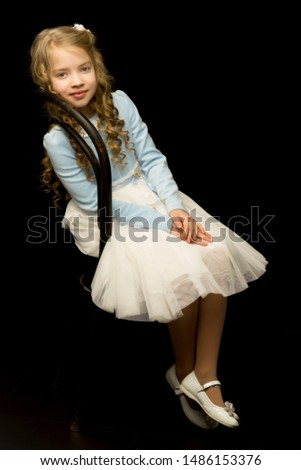 Portrait of a little girl sitting on an old Viennese chair, blac