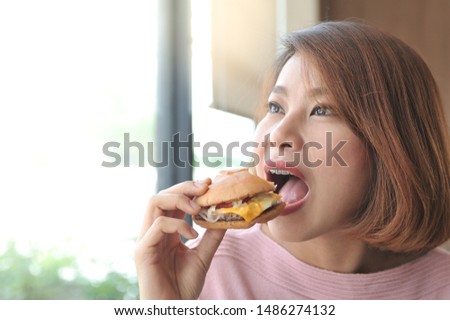 A women enjoy eating with her burger in hands,asian women open her mouth for biting burger,Selective focus