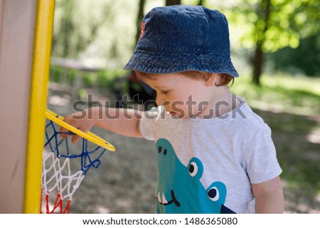 2 year old boy in a playground. summer day in the yard. that's how you becoming a basketball master.