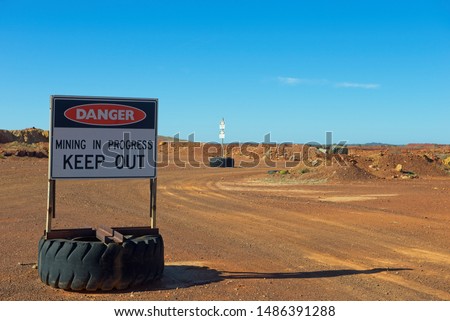 Danger Sign at Mining Site, with red sand and sunny blue background with copy space.