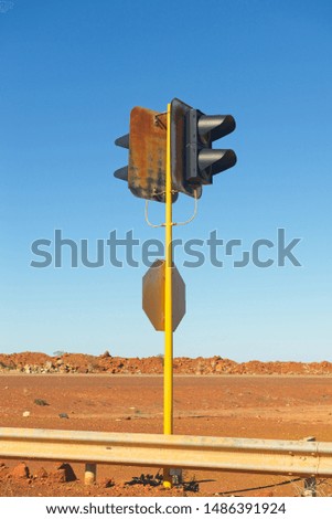 Out of service traffic light on yellow pole at remote outback highway in Australia, with red soil and sunny blue sky as background and copy space.
