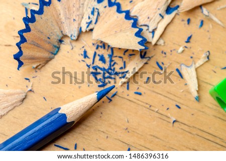 Close-up of a bright blue pencil just sharpened with a sharpener lying next to the chips on the table. The concept of drawing and creativity of children