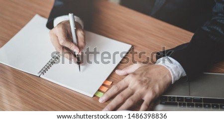 Close-up view of businessman writing his idea for his project on notebook in modern office room